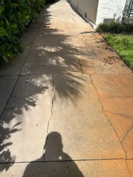 Concrete walkway with several cracks and rust-colored stains
