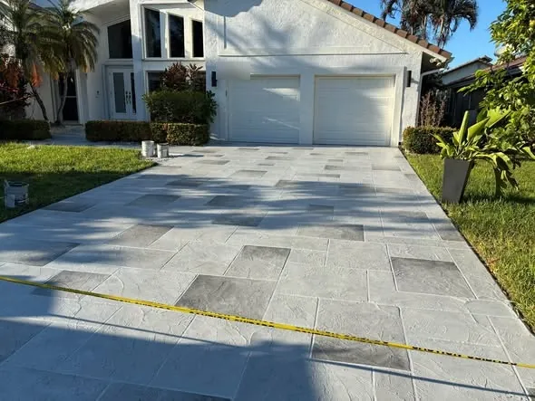 Driveway resurfaced with a grey slate-pattern overlay in front of a two-car garage