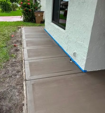 Fresh-poured concrete walkway sections along the side of a house