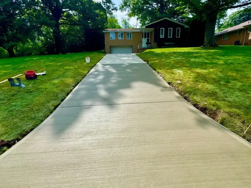 Long concrete driveway with a fresh broom finish leading up to a house