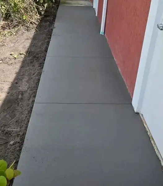 New concrete sidewalk running along the side of a red house
