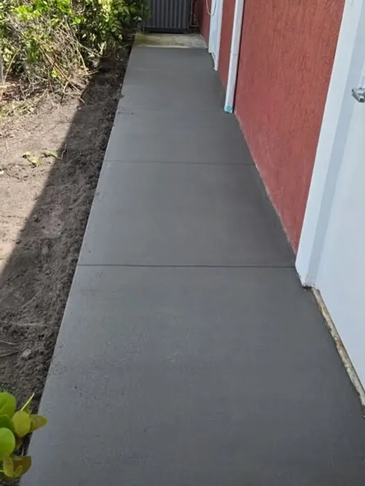 New concrete sidewalk running along the side of a red house