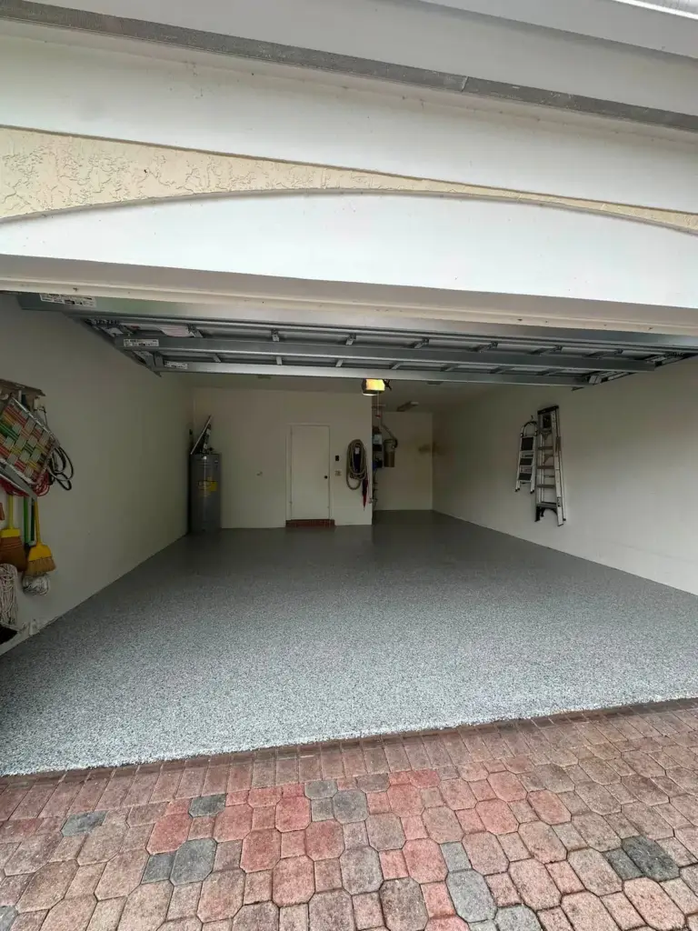 Single garage with a grey speckled floor coating and paver apron